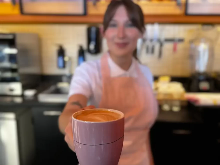 Barista biedt koffie aan in koffiebar Groningen